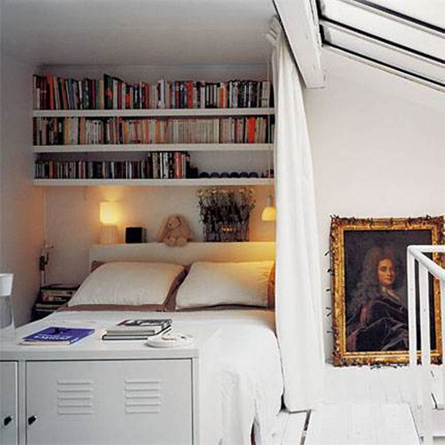 Dormitorio con cama en una esquina y sobre ella repisas de muro a muro que sirven de biblioteca