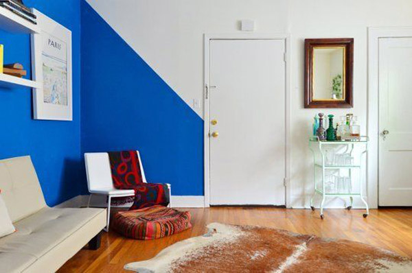 Sala de estar con un pared azul que termina en diagonal para comenzar la siguiente pared en blanco.
