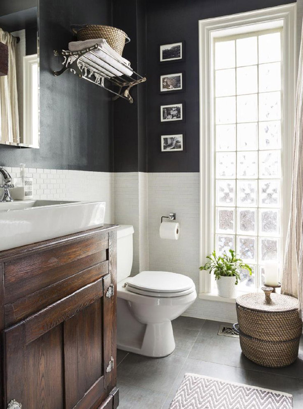 Baño con pared de pequeños ladrillos en blanco. La parte superior de las paredes, lisas y en negro. Ventanal con marco blanco de madera.