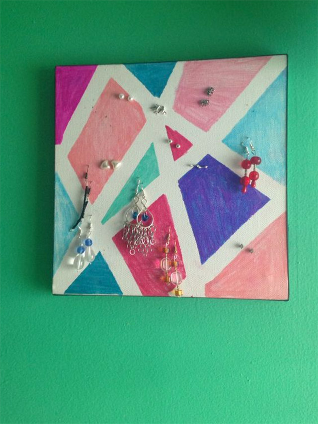 Canvas con pintura geométrica abstracta y aros pinchados sobre el lienzo.