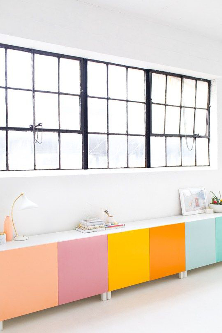 mueble estilo arrimo o rack junto a la ventana donde cada puerta tiene un color liso distinto