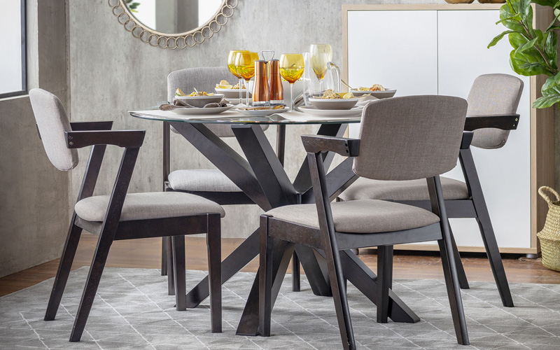 Comedor redondo con base de madera y superficie de vidrio transparente. Ocupa poco espacio visual y luce la vajilla.