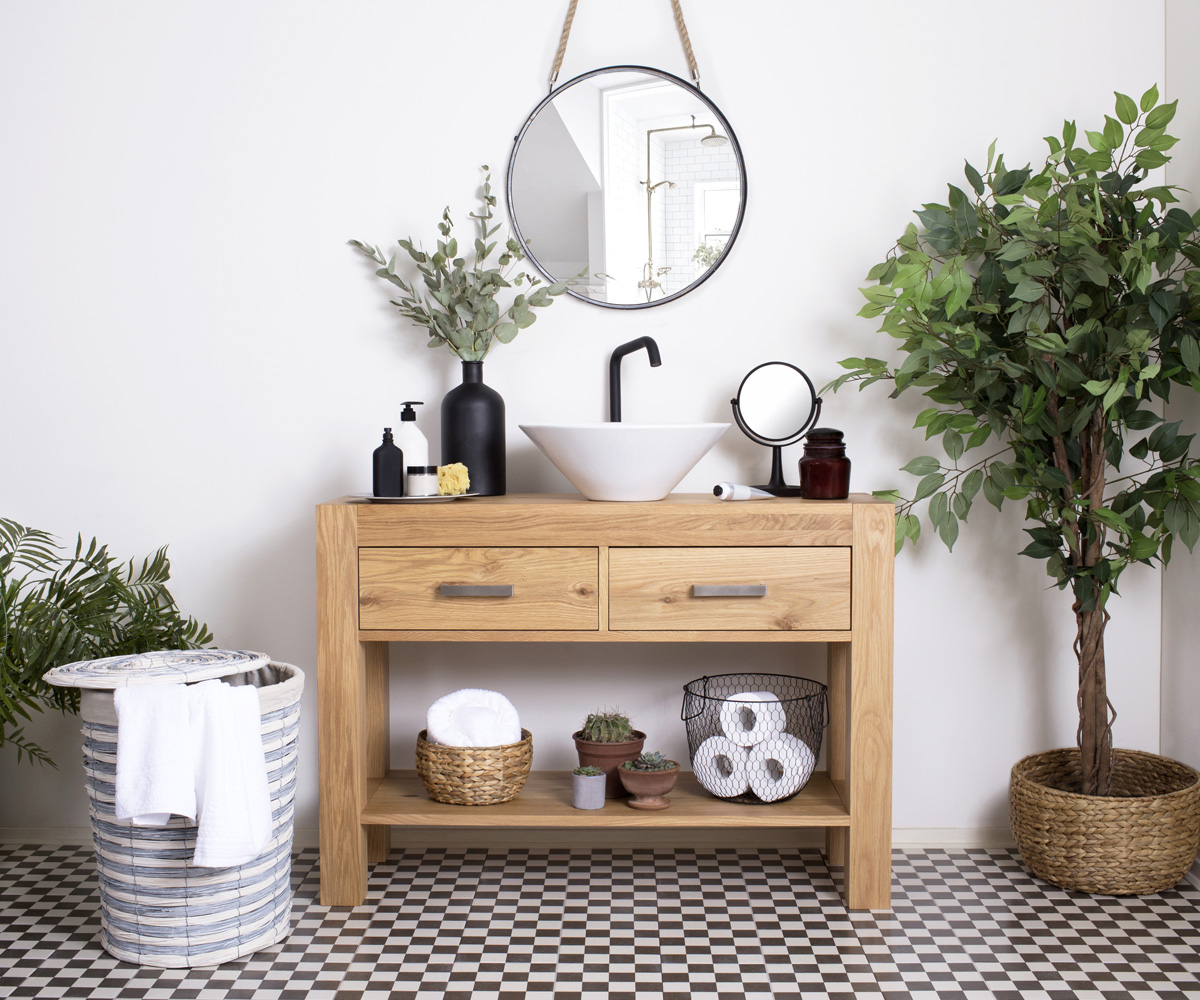 Lavamanos cerámica blanca con mueble de madera piso ajedrez cestos de fibras naturales y plantas de interior
