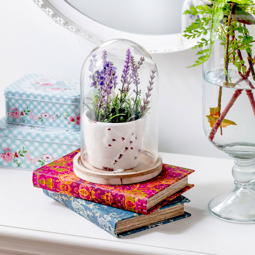 Detalle de la superficie de un recibidor con libros, floreros y adornos en su superficie