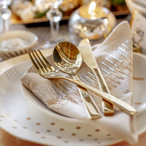 Detalle de cubiertos, tenedor, cuchara y cuchillo dorados.