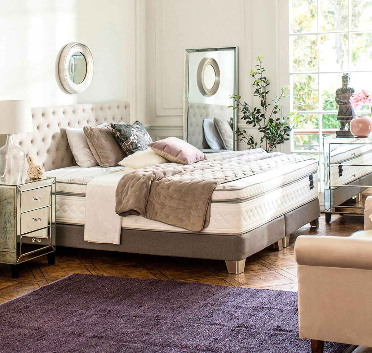 Imagen de dormitorio glam con velador espejado, respaldo de capitoné y colores dorados y tierra.