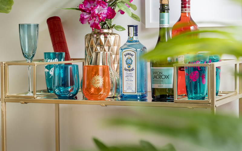 Carro bar dorado con vasos y botellas