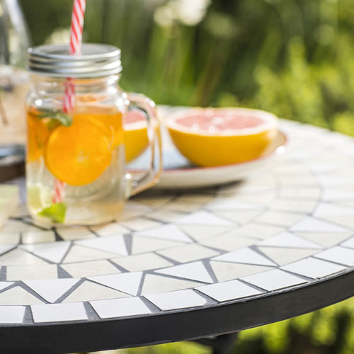Mesa de cerámica con un vaso con agua y naranjas en su interior para saborizar