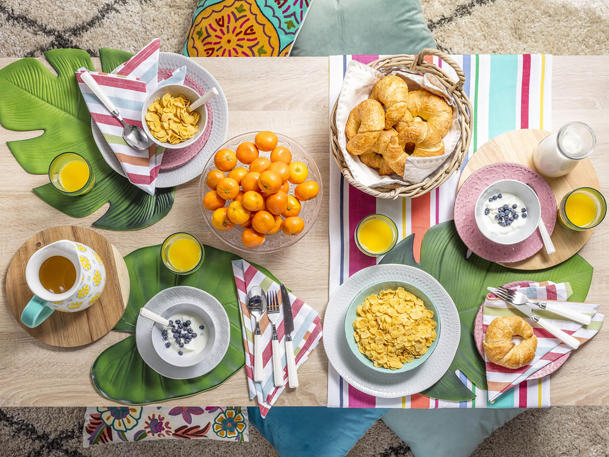 Frutas, medialuna, cereales, yogurt y arándanos para un desayuno decorado con la mejor vajilla, individuales y textil