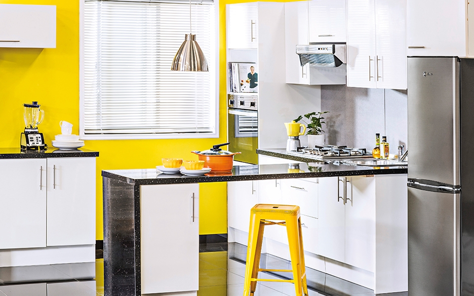 Cocina tipo americana, con paredes color amarillo y muebles blancos